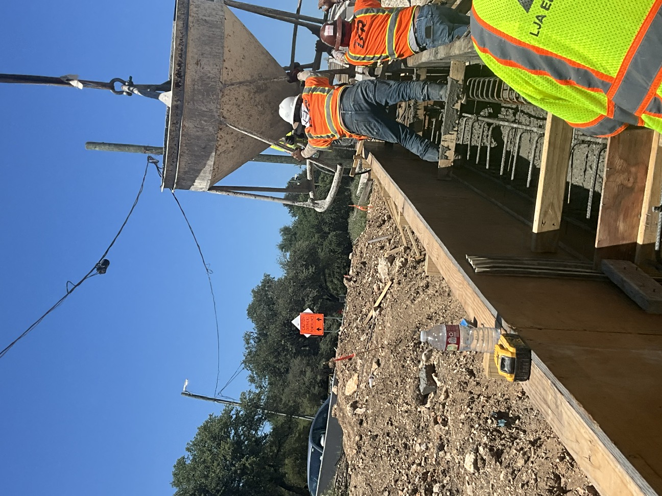 Wide shot of construction workers placing foundation for the new traffic rail